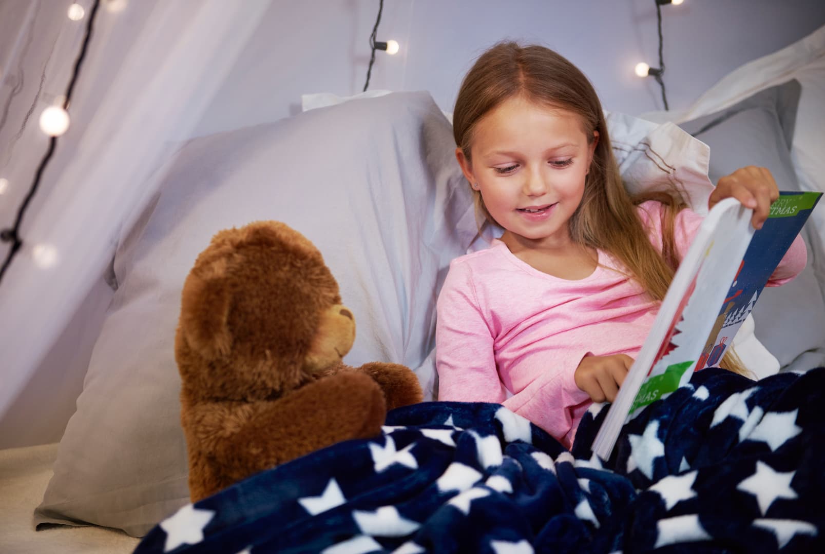 girl watching picture book with teddy bear 1